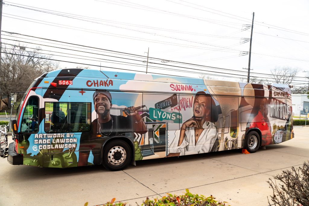 Photo of colorful bus parked outside on a cloudy day. The bus wrap design shows portraits of Chaka, Suzanne McFayden, and Sam Mays.